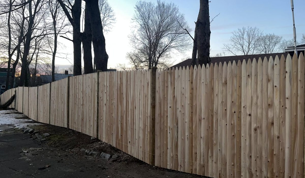 Tree care and landscaping maintenance around residential wooden fence to protect property and improve outdoor safety