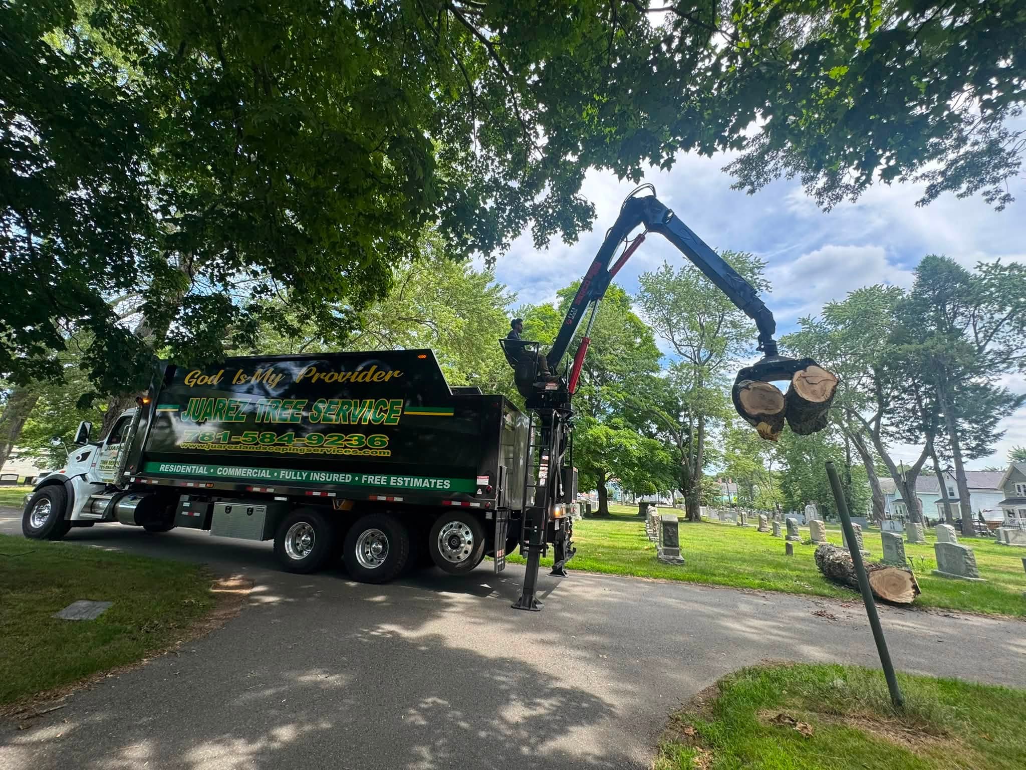Grapple truck lifting large tree logs during professional tree removal by Juarez Landscaping and Tree Services.